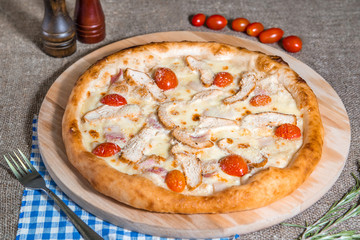 homemade pizza with cheese, tomato, bacon, ham on sackcloth background