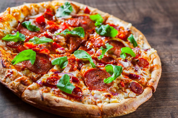 sliced Pepperoni Pizza with Mozzarella cheese, salami, chorizo, tomato sauce, pepper, Spices and Fresh arugula. Italian pizza on wooden table background
