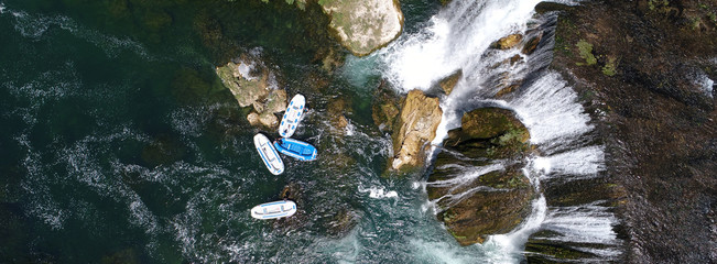 group of people doing white water rafting activity on wild river with waterfall