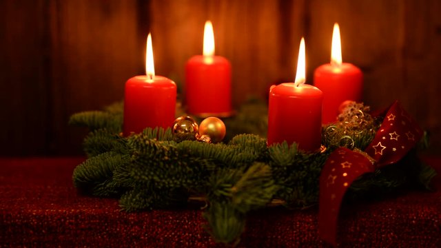 adventskranz mit 4 roten brennenden kerzen mit Holzhintergrund