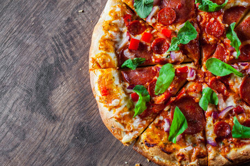 sliced Pepperoni Pizza with Mozzarella cheese, salami, chorizo, tomato sauce, pepper, Spices and Fresh arugula. Italian pizza on wooden table background