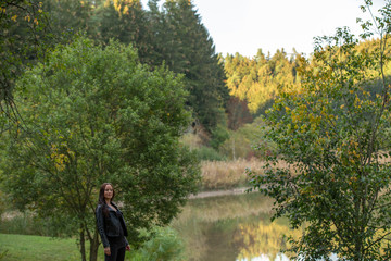 Brunette in a black leather jacket near the lake admires a rainbow