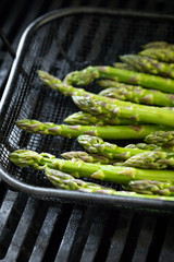 Roasting asparagus spears in a barbecue grilling basket