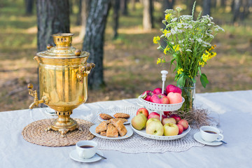 Traditional samovar on a table with snacks and field flowers bouquet outdoor