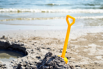 Plastic toy shovel in yellow sand on the beach