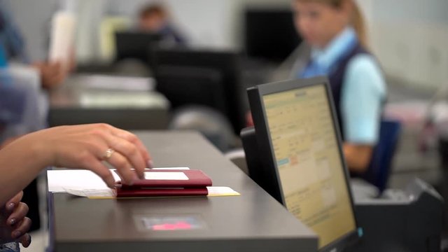 airport employee checking passport of people passengers on border and selling tickets in airport counters. check-in on board aircraft, close up, close-up, Checking passports at the airport check in.