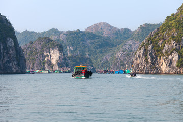 Naklejka premium Ha Long Bay, Vietnam-December 20, 2013. Common life scene with fishing boats and commuting people at floating fishing village on December 20, 2013 in Ha Long Bay of northeast Vietnam.