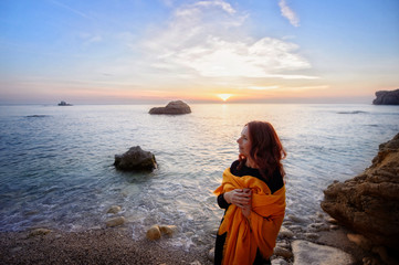Beautiful woman walking along the coast of the sea at sunset