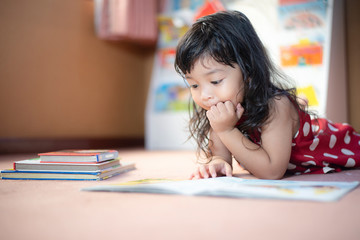 A cute little child Asian girl doing homework and reading a book. Kid enjoy learning with happiness at home. Clever,Education and smart learning concept