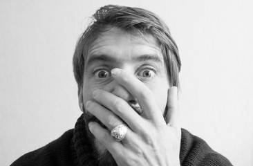 A man is afraid and covers his face with his hands