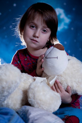 Little cute child girl pretending mom, playing and puts teddy bear in bedю  Happy carefree...