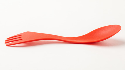 Red, light, plastic travel spoon fork on white background.