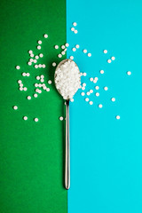 Sugar-replacing tablets with a spoon on a green and blue background.