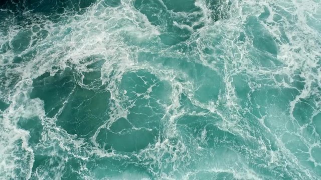 Aerial shot of a turquoise ocean boiling with foamy storm waves. 4K, UHD