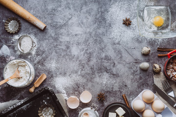 Healthy baking ingredients. Spoon with flour, dishes, eggs, butter salt and rolling pin on a grey background.Bakery background frame. Top view, copy space.