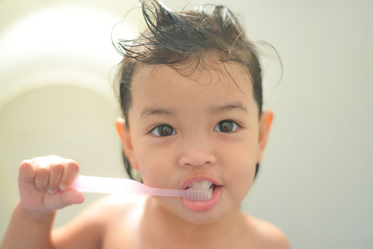 dental hygiene. happy Asian little girl or kid brushing her teeth by toothbrush in the bathroom. Healthcare concept.