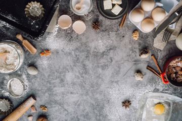 Healthy baking ingredients. Spoon with flour, dishes, eggs, butter salt and rolling pin on a grey background.Bakery background frame. Top view, copy space.