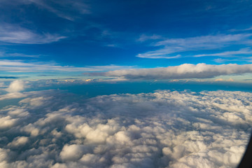 Naklejka na ściany i meble Aerial view from airplane window. Aircraft flying above land with beautiful clouds in the blue sky background. Aviation concept. Tourism,Journey,Travel concept.