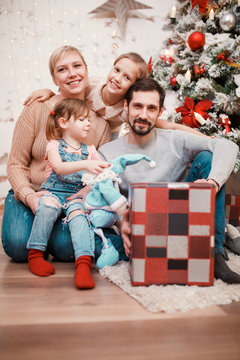 New Year's picture of parents with daughters on background of decorated pine