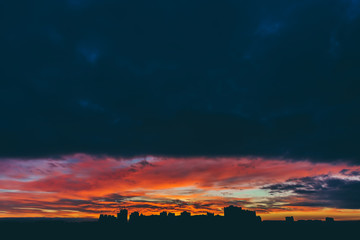 Cityscape with wonderful varicolored vivid dawn. Amazing dramatic multicolored cloudy sky above...