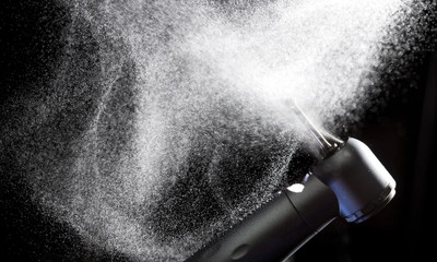 Dental handpiece with diamond bur and water splash motion on dark background.