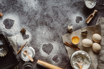 Healthy baking ingredients. Background with flour, rolling pin, eggs, and heart shape on kitchen gray kitchen table.  Top view for Valentines day cooking. Copy space.