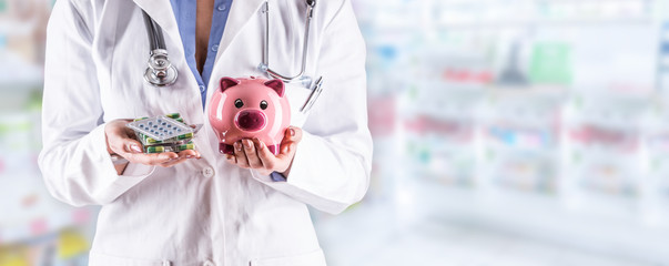Doctor woman hands holding pills and piggy bank. Blurred pharmacy interior in the background