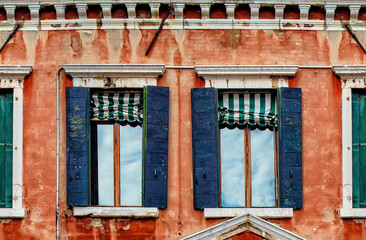 Fototapeta na wymiar Second floor of old red house facade with wooden dark blue windows
