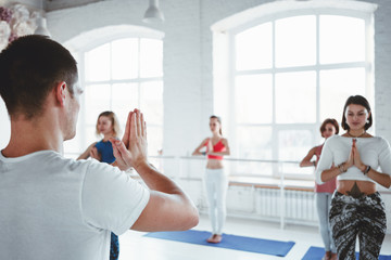Fototapeta na wymiar Male coach practice yoga exercise with woman group indoor gym. Together fit training. Woman health care. Healthy lifestyle concept