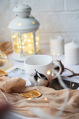 Autumn still life from pumpkin, leaves, pine cones, candles, scarf, red mug of cocoa, coffee or hot chocolate with marshmallow on warm plaid with garland.
