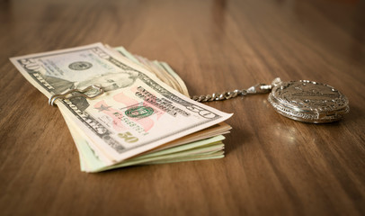Clock and banknotes on brown table. Time is money concept
