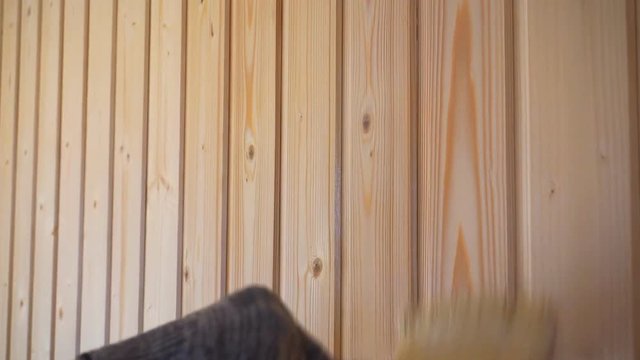 Worker&rsquo;s hand holds a brush and paints a wooden wall, wall cladding, floor or wall surface. 1920X1080 Full Hd.