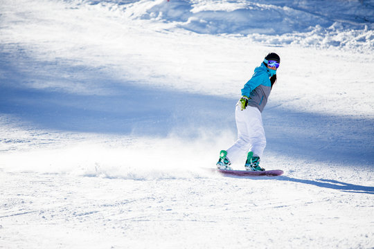 Photo of sports woman snowboarding on snowy slope