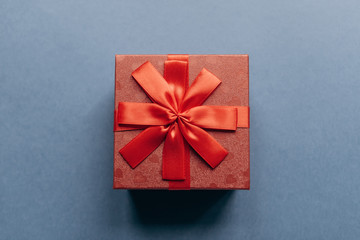 Red box with a bow with a gift on a blue background.