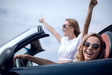 close up.two girlfriends traveling in a convertible car