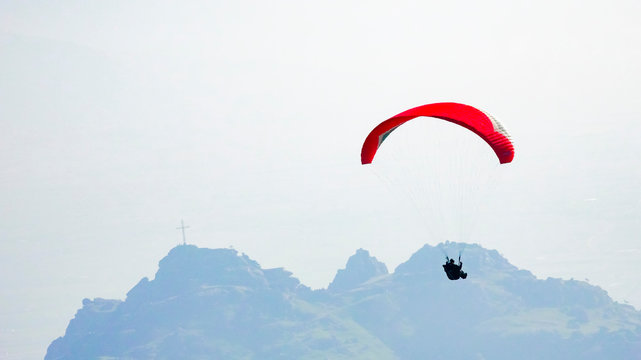 Paraglider silhouette flies paraglider in the sky high over mountain summit. Paragliding