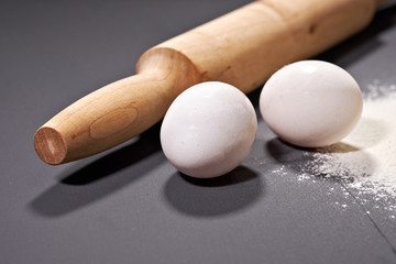 rolling pin, eggs, flour on grey background, selective focus