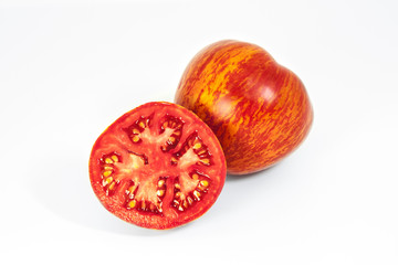Whole tomato and a half cut tomato on a white background. Ripe motley tomatoes with unusual natural pattern.