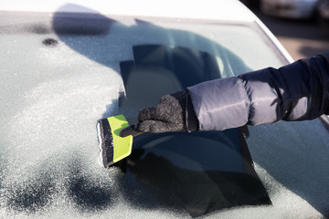 Hand in glove cleans window of the car from ice - obrazy, fototapety, plakaty