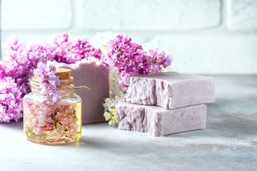 Obraz na płótnie Canvas Handmade soap, Glass jar with fragrant oil and lilac flowers for spa and aromatherapy.