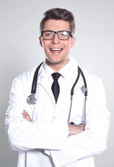Handsome doctor is looking at camera while standing with folded 