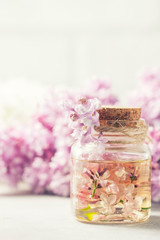 Glass jar with aroma oil and with lilac flowers for spa and aromatherapy. Spa concept.