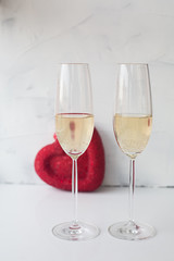 two festive glasses with champagne on a white background with a red heart