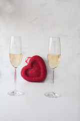 two festive glasses with champagne on a white background with a red heart