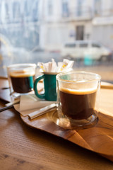 Wooden tray with two cups of coffee on the table in front of the window