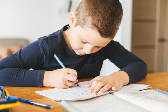 Schoolboy doing his homework on desk at home.