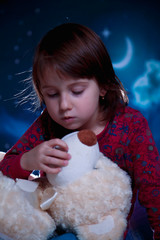 Sweet dreams. Little cute child girl pretending mom, playing and tells a fairy tale to teddy bear...