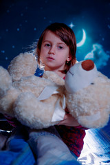 Sweet dreams. Little cute child girl pretending mom, playing and puts teddy bear in bedю  Happy...
