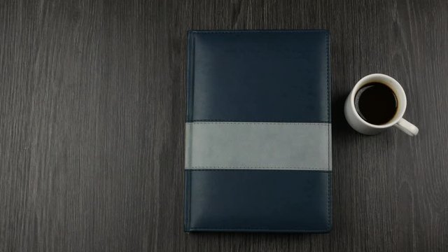 Grey covered notepad and cup of cofee on dark wooden background. Opening a notepad for writing.