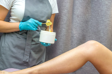 Girl cosmetician in medical gloves with pasta for shugaring